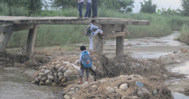 鉄砲水で損壊した橋と通学する子どもたち。